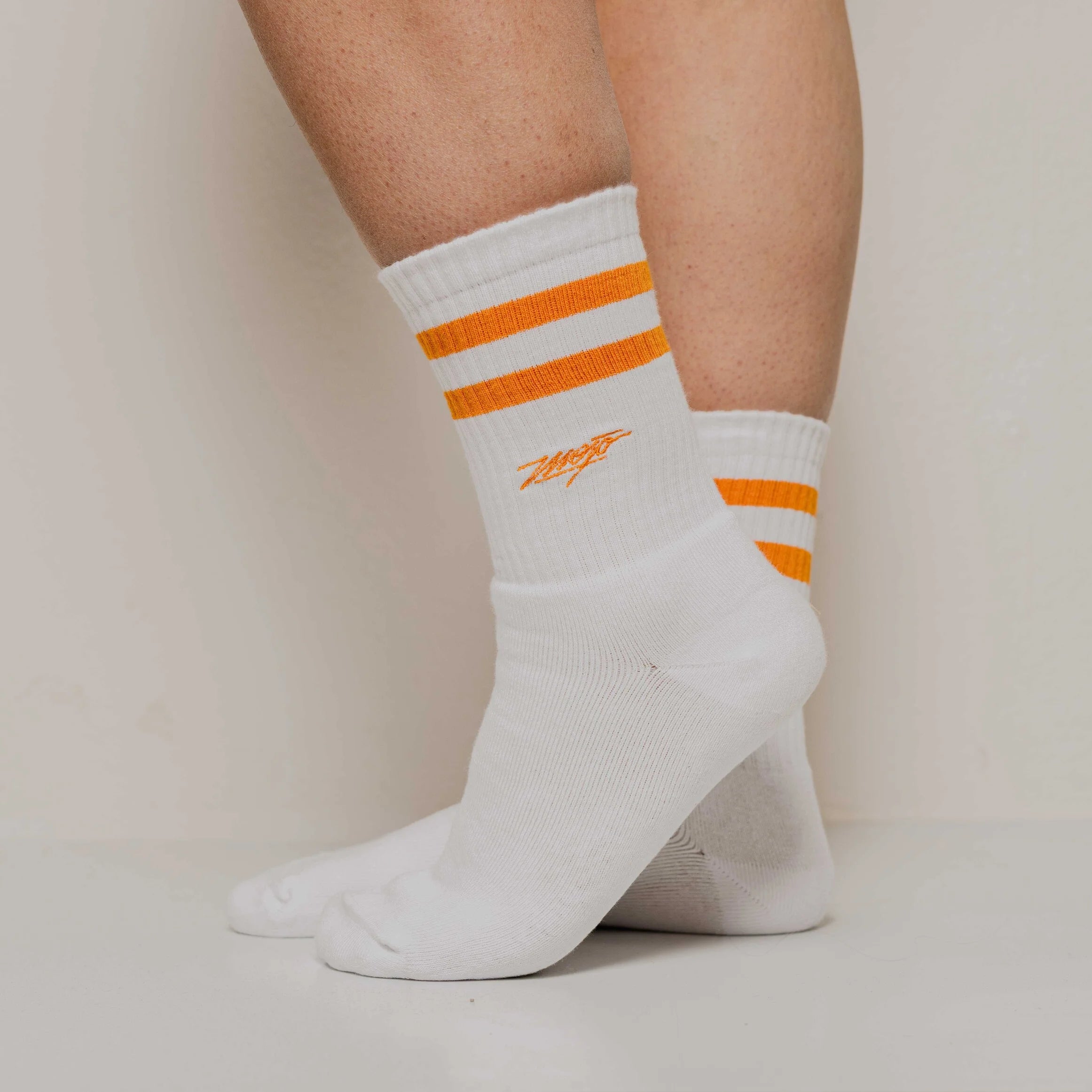 White socks with orange stripes and a logo on a neutral background