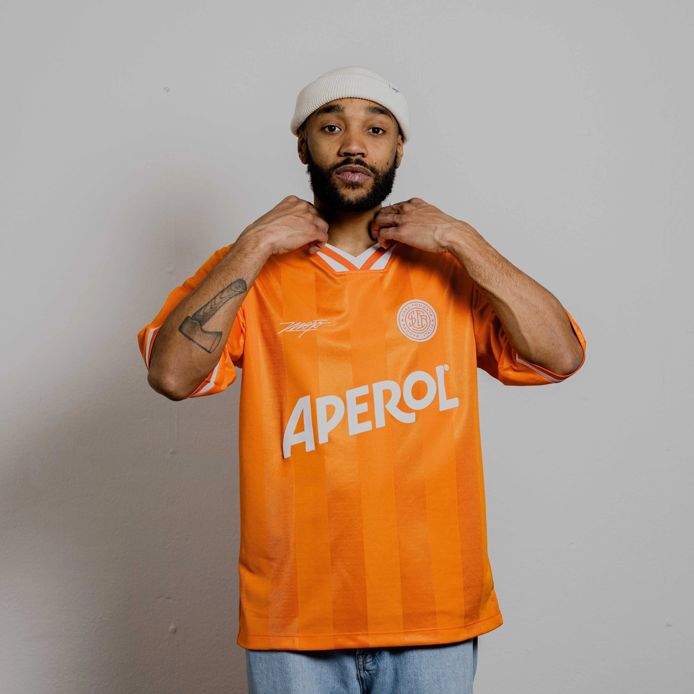 Person wearing an orange jersey with 'Aperol' branding against a plain background