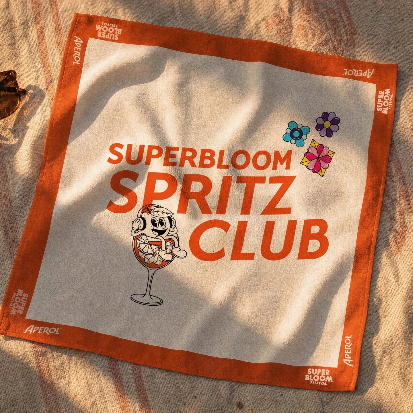 Aperol x SUPERBLOOM Satin-Bandana in Weiß und Orange mit Spritz Club Logo und Figur im Glas.