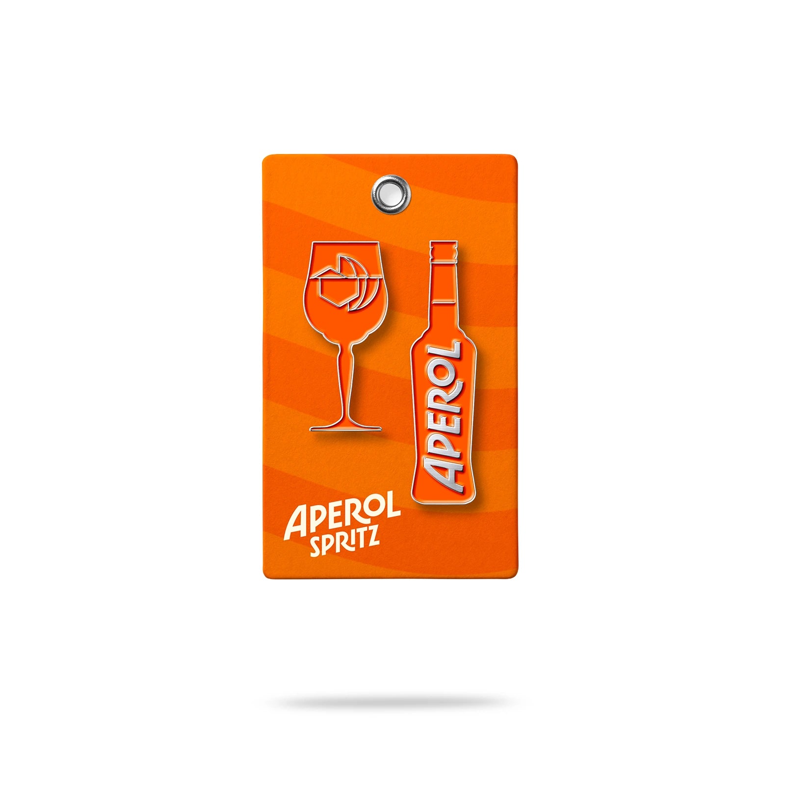 Two enamel pins on an orange wavy background card: one shaped like an Aperol Spritz glass with ice cubes, the other shaped like an Aperol bottle with the logo.