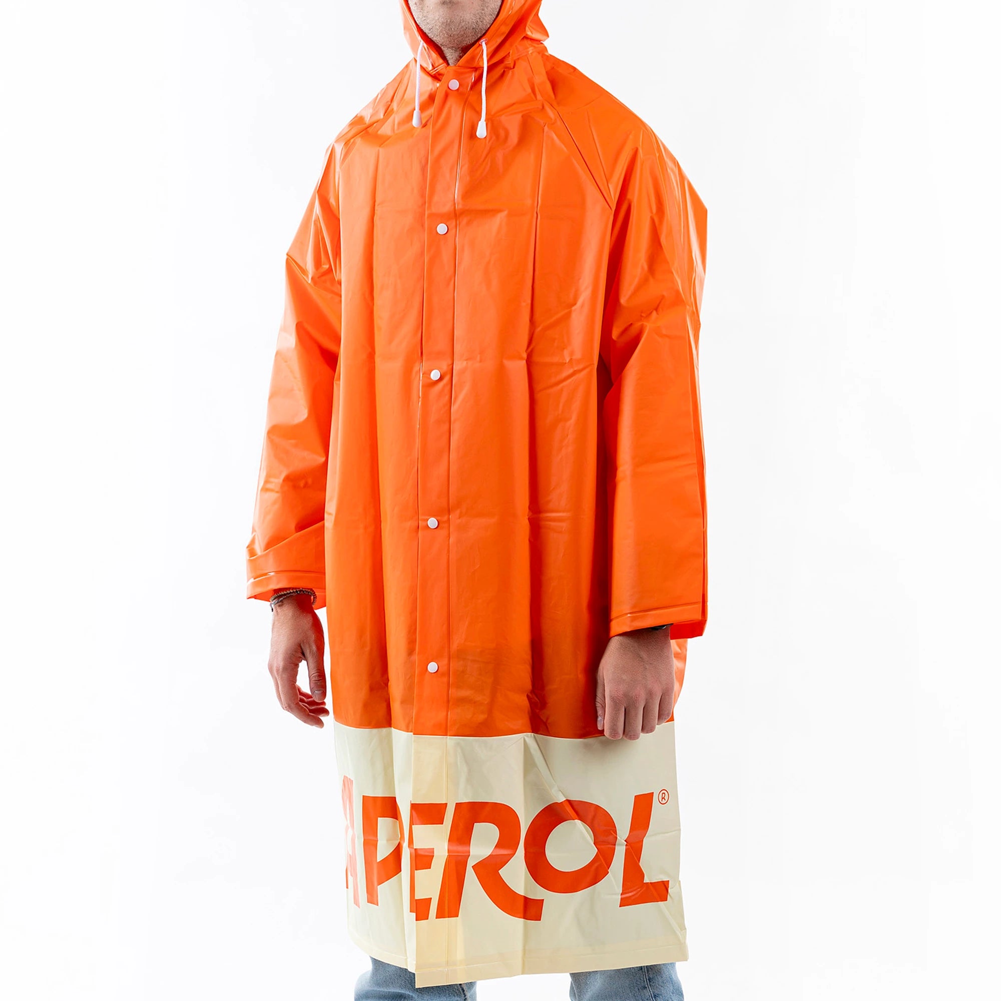 Person modeling an orange Aperol Spritz raincoat with hood and front buttons, featuring the large "APEROL" logo on the cream-colored lower section.