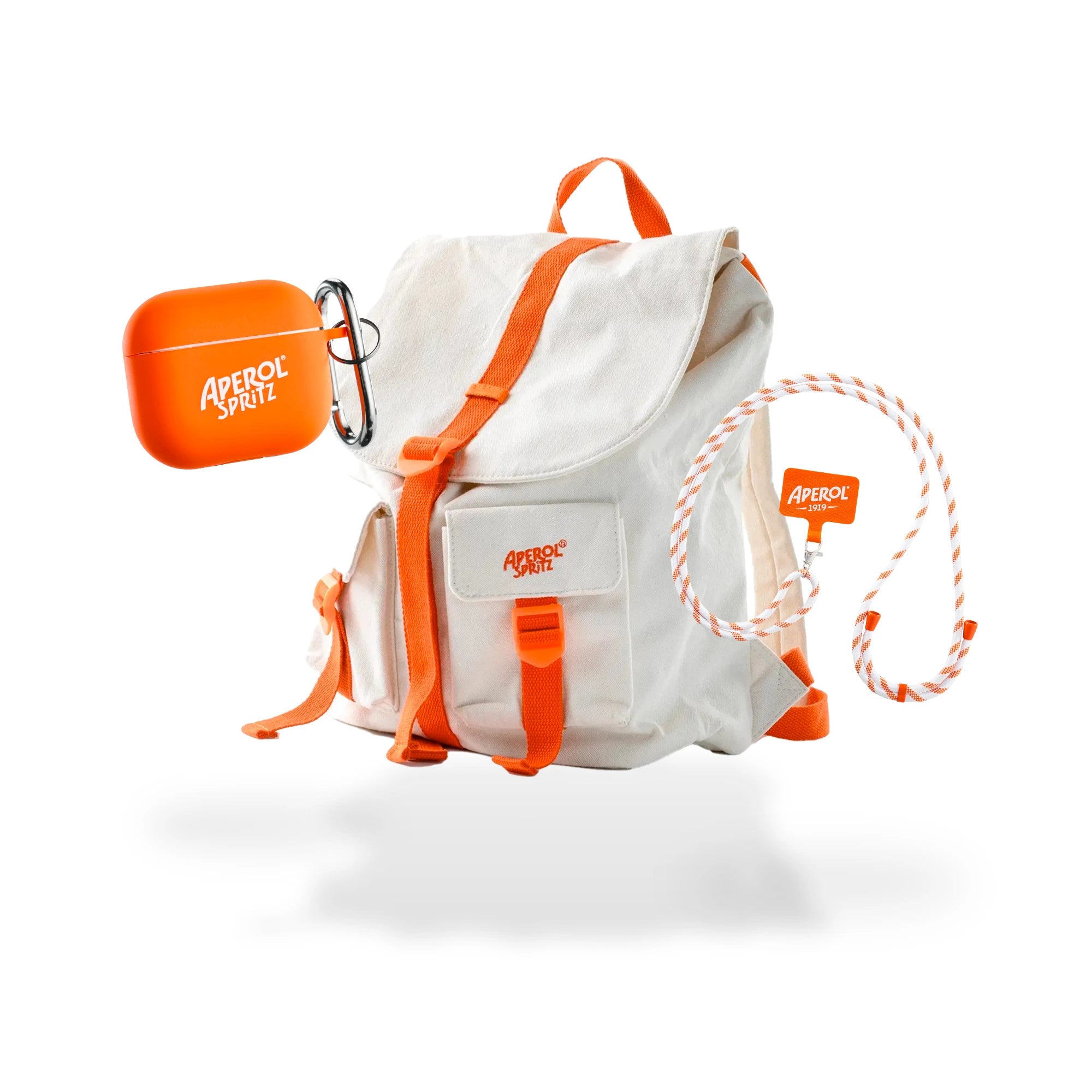 Aperol travel bundle featuring a cream canvas backpack with orange straps, an orange wireless earbuds case with a carabiner, and a white-and-orange striped lanyard with branded clip.