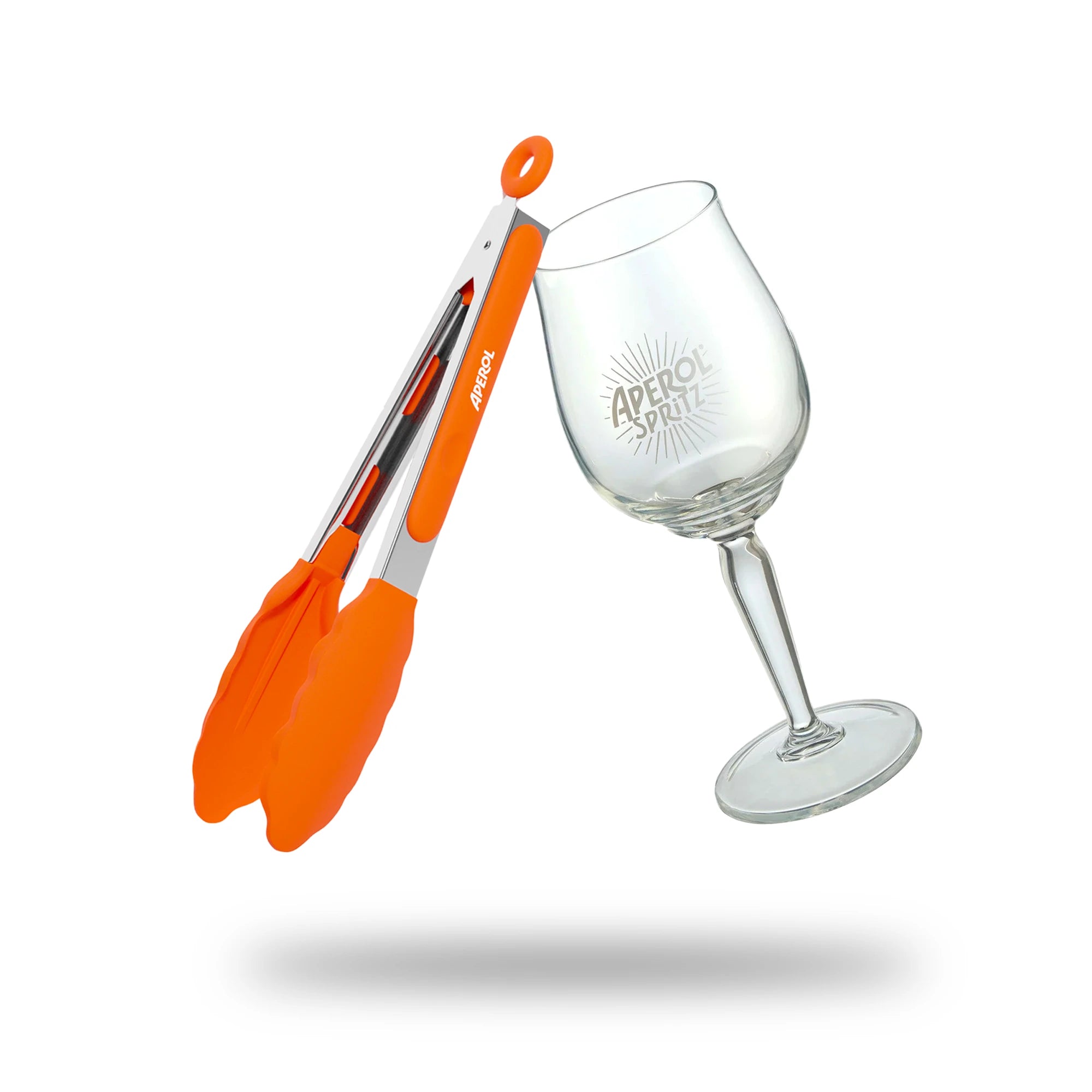 Aperol-branded BBQ bundle featuring stainless steel tongs with bright orange silicone grips and a clear wine glass etched with the Aperol Spritz logo, displayed on a white background with a soft shadow.