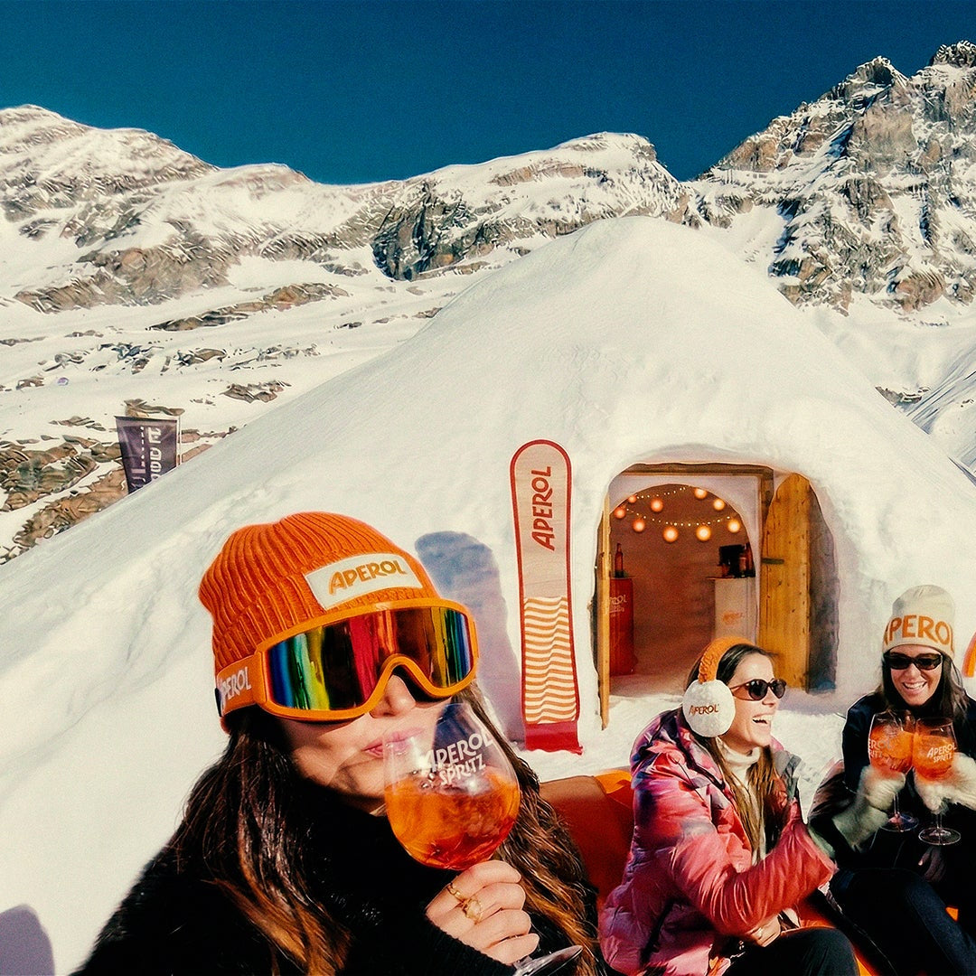 People sitting in front of a snow-themed vehicle with a mountainous background