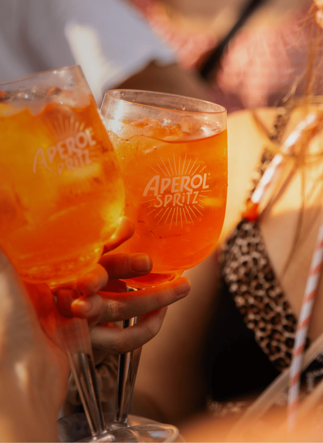 Two Aperol Spritz glasses raised for a toast.