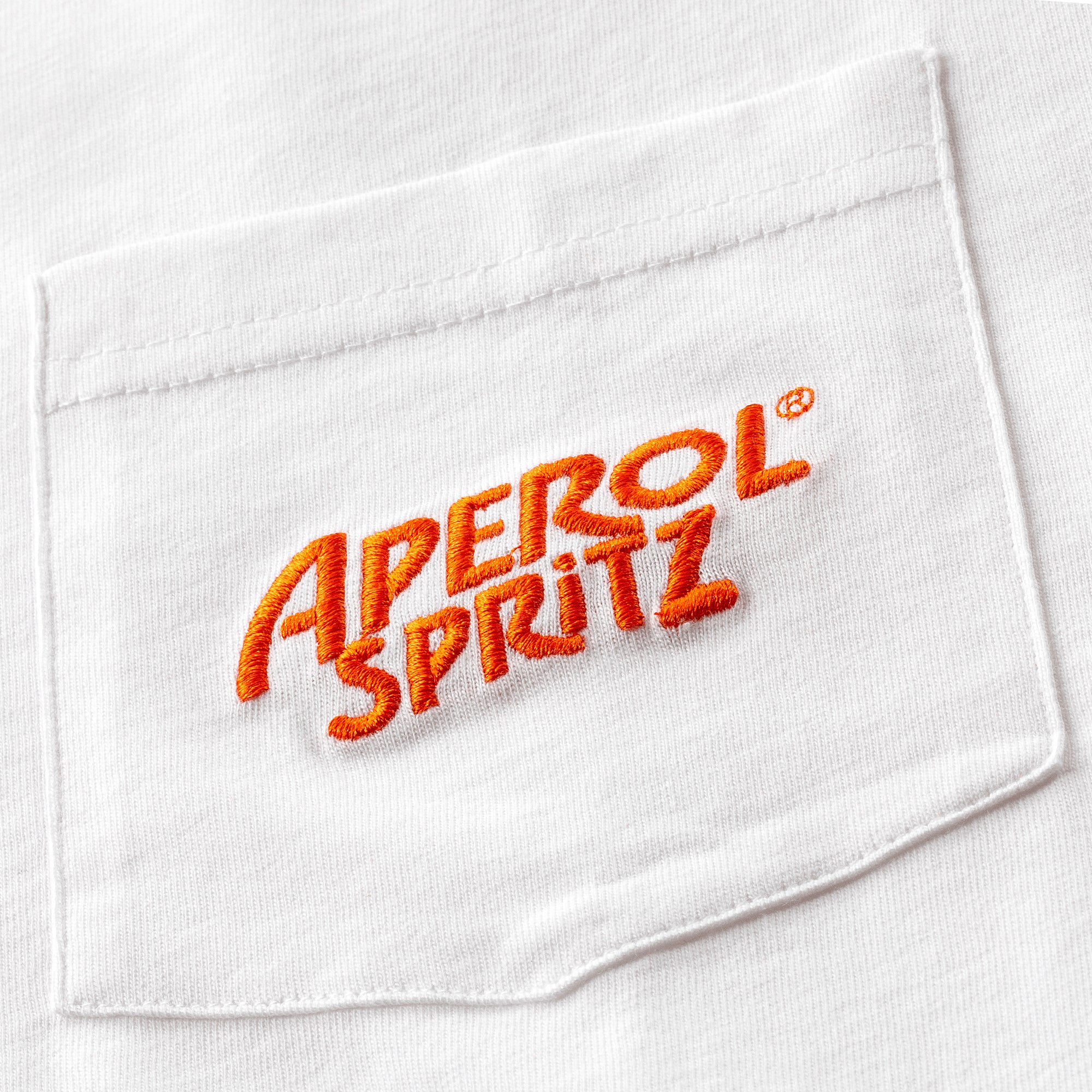 Close-up of a white t-shirt pocket with the Aperol Spritz logo embroidered in orange thread.