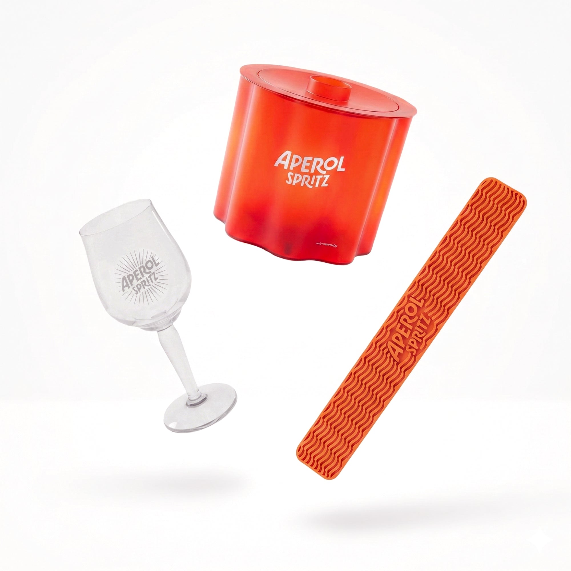 Aperol Spritz-themed glass, ice cube tray, and bar spoon on a white background