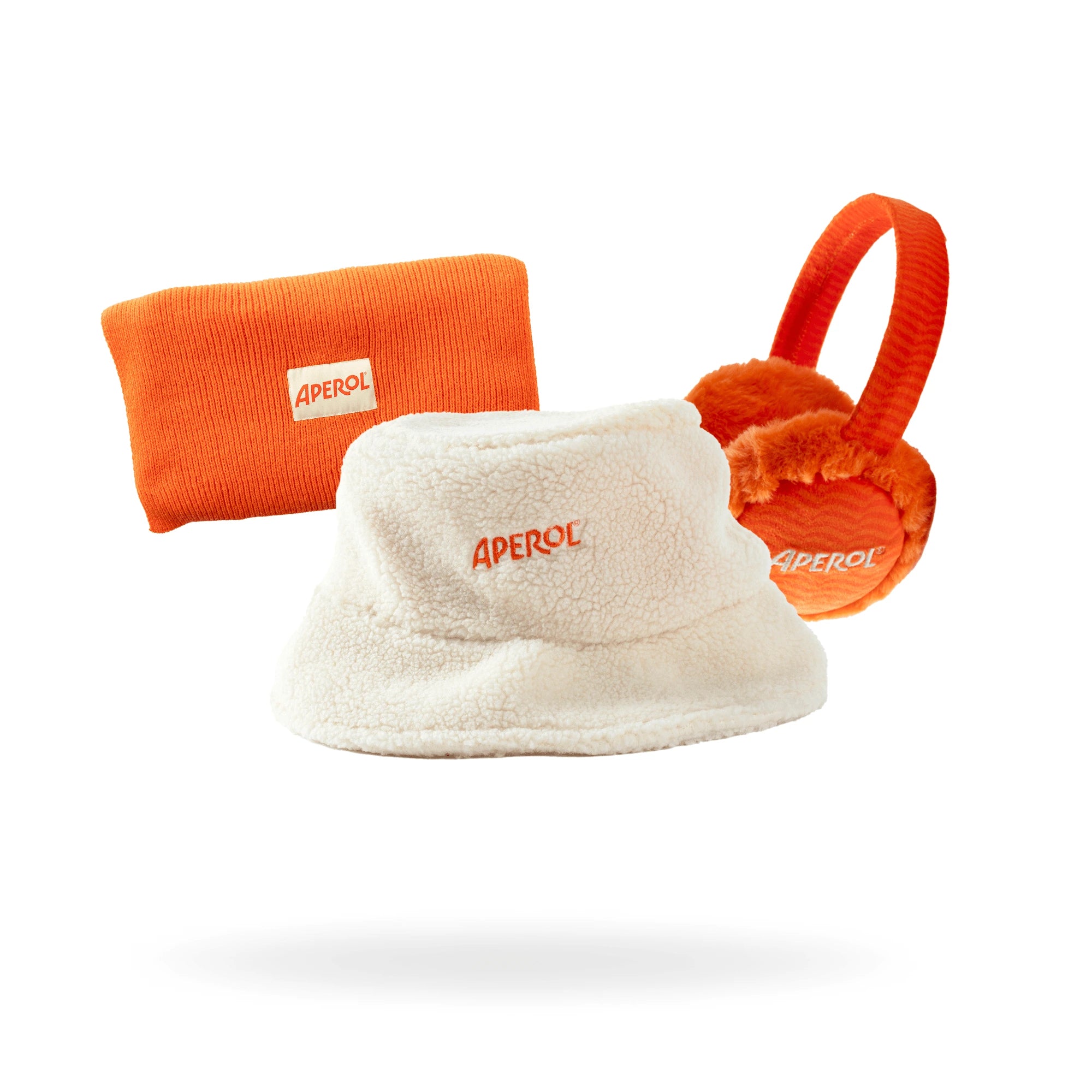 Winter accessory set featuring Aperol-branded earmuffs, an orange beanie, and a white sherpa bucket hat, displayed against a white background.