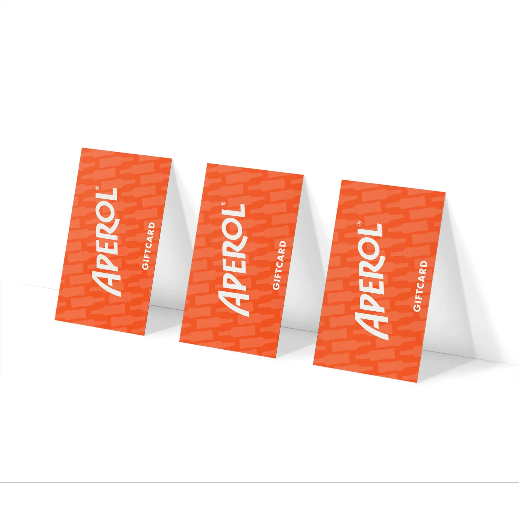 Three orange Aperol gift cards standing upright against a white surface, each featuring the word 'APEROL' in bold white letters with a subtle bottle pattern in the background.